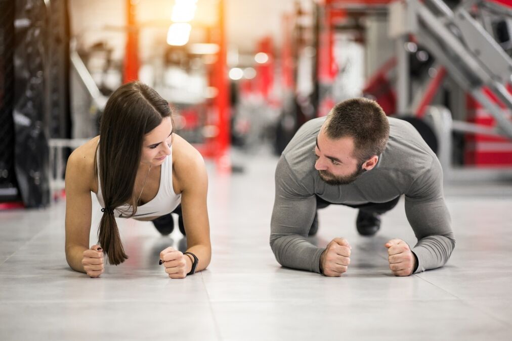 Ένας άνδρας και μια γυναίκα εκτελούν την άσκηση Plank, σχεδιασμένη για όλες τις μυϊκές ομάδες